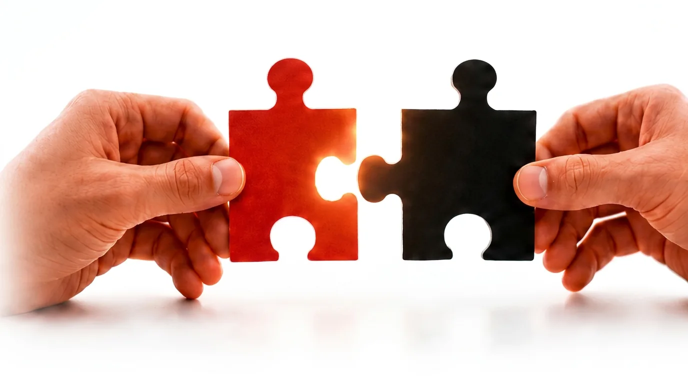 Two hands joining a red and a black puzzle piece